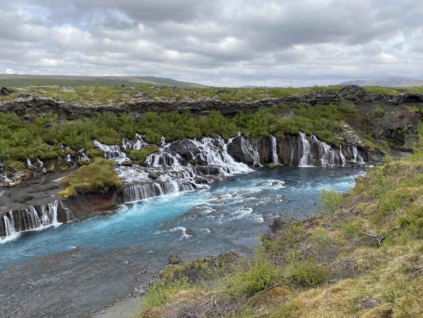 Margir litlir fossar falla niður kletta ofan í á.